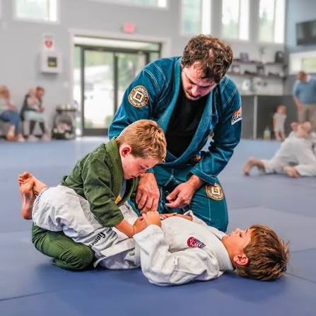 Youth BJJ class with coach and kids on mats